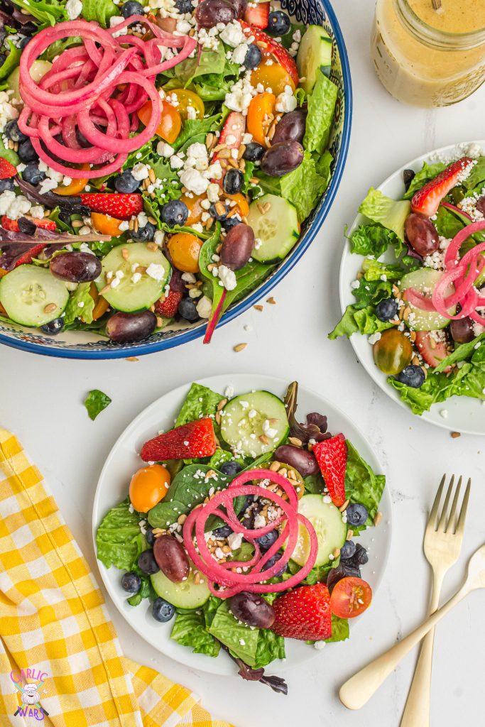 two bowls of summer salad with large salad serving bowl